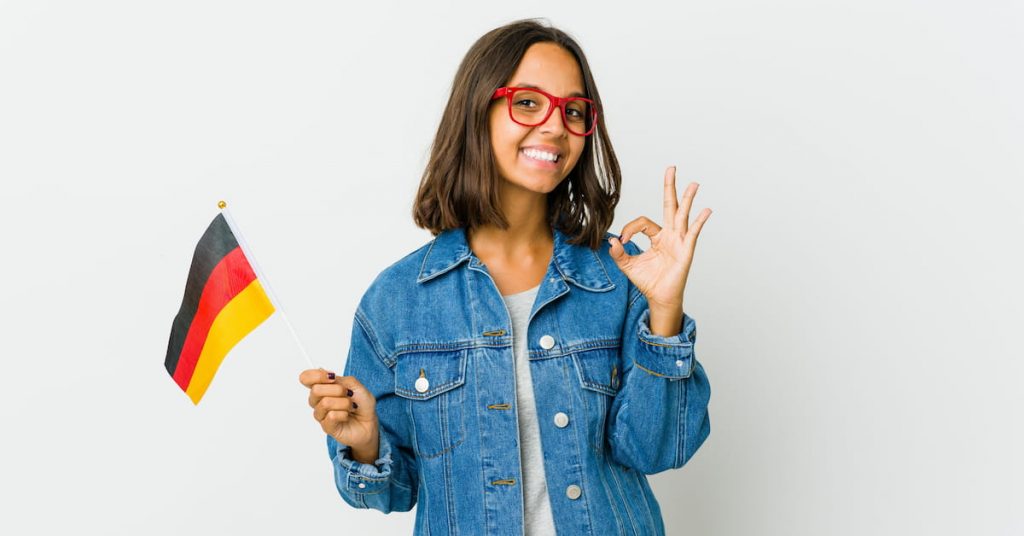 Young lady standing with the German flag in one hand and an 'O.K' sign